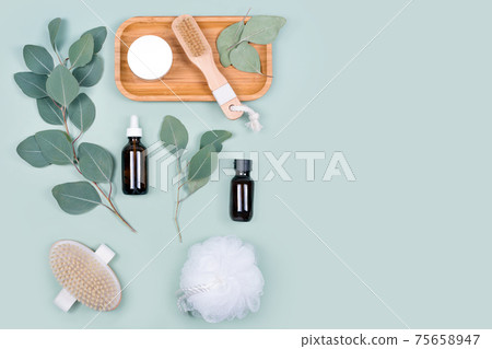 Essential oils, facial creme container and massage brushes with natural eucalyptus leaves on green background. Beauty products, massage tools, facial skin care, spa beauty treatment concept. Flat lay Essential oils, facial creme container and massage brushes with natural eucalyptus leaves on green background. Beauty products, massage tools, facial skin care, spa beauty treatment concept. Flat lay 75658947