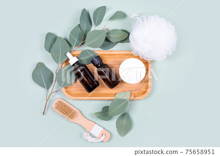 Essential oils, facial creme container and massage brushes with natural eucalyptus leaves on green background. Beauty products, massage tools, facial skin care, spa beauty treatment concept. Flat lay Essential oils, facial creme container and massage brushes with natural eucalyptus leaves on green background. Beauty products, massage tools, facial skin care, spa beauty treatment concept. Flat lay 75658951