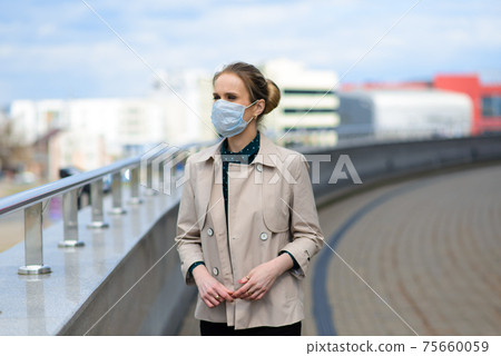 A young businesswoman wearing a health mask and talking on the phone in the city 75660059