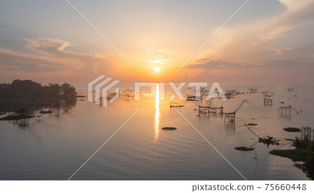 Local fishing trap net in canel, lake or river at sunset. Nature landscape fisheries and fishing tools lifestyle at Pak Pha, Phattalung, Thailand. Aquaculture farming. 75660448
