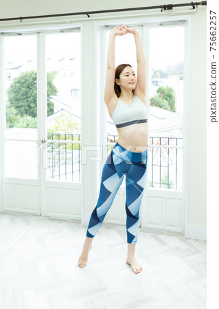 A woman stretching in her room A woman stretching in her room 75662257