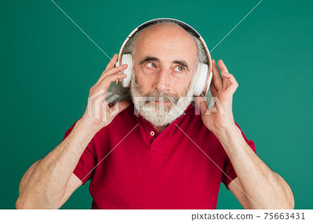 Close-up senior grey-haired man in headphones isolated over green background. 75663431
