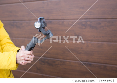 A man holds a stabilizer for smartphones. Mobile shooting on the street. A man holds a stabilizer for smartphones. Mobile shooting on the street. 75663691