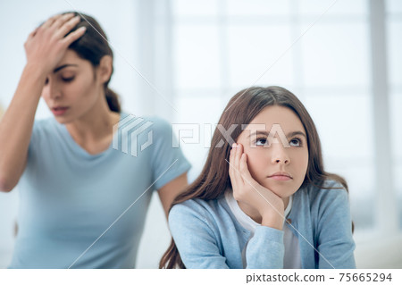 Stubborn teen daughter and upset mom behind 75665294