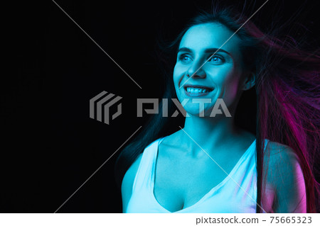 Portrait of young beautiful girl isolated on dark background in neon light 75665323