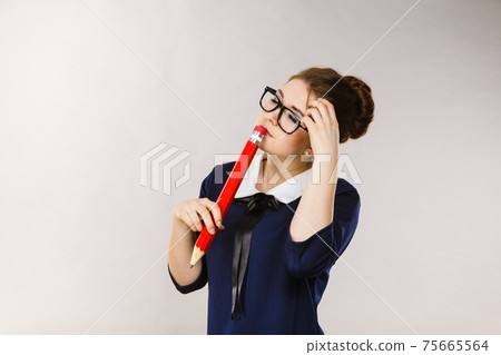 Woman confused thinking, big pencil in hand 75665564