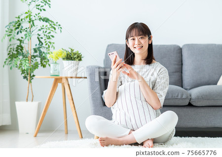 Young woman looking at her smartphone in the living room 75665776