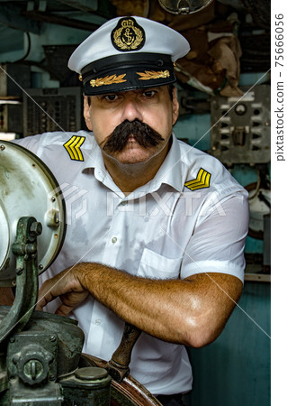 Captain standing in the wheelhouse of ship and looking to camera. 75666056