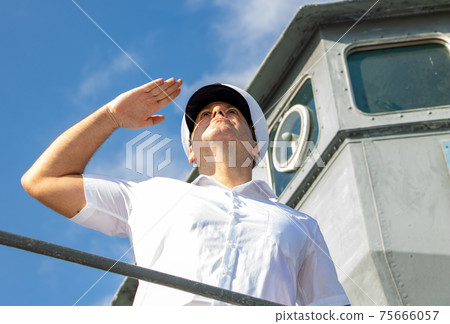 The captain standing on the gallery of navigation bridge of ship and salute. 75666057