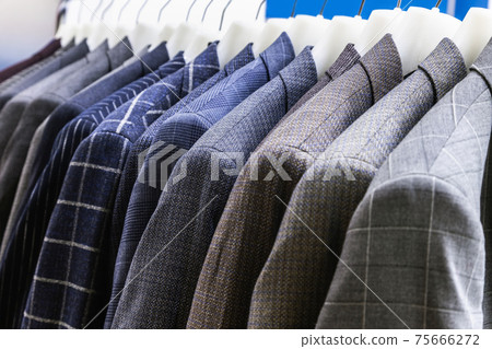 men's jackets in check and stripes hang on hangers in the atelier 75666272