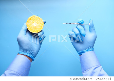 hand in medical gloves holding syringe and slice of a orange , top view hand in medical gloves holding syringe and slice of a orange , top view 75666471