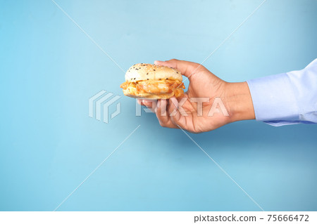 hand holding beef burger against blue backgrund with copy space hand holding beef burger against blue backgrund with copy space 75666472