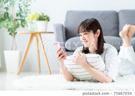 Young woman looking at her smartphone in the living room Young woman looking at her smartphone in the living room 75667050