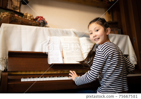 A girl playing the piano A girl playing the piano 75667581