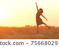 Elegant woman with long hair in long dress dancing elegant on sand in desert. Sunrise, backlight photo 75668029
