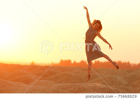 Elegant woman with long hair in long dress dancing elegant on sand in desert. Sunrise, backlight photo Elegant woman with long hair in long dress dancing elegant on sand in desert. Sunrise, backlight photo 75668029