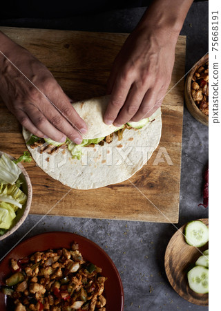 young man rolls a durum or a burrito young man rolls a durum or a burrito 75668191