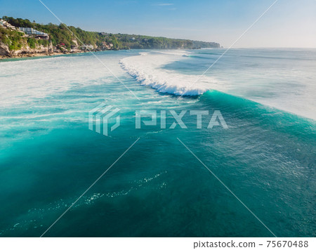 Blue wave in tropical ocean at Padang Padang, drone shot. Aerial view of barrel waves Blue wave in tropical ocean at Padang Padang, drone shot. Aerial view of barrel waves 75670488