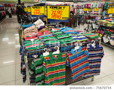 SEREMBAN, MALAYSIA -MARCH 2021: Various types of clothes are being sold in supermarkets. Displayed by hanging or placed in a container. Price tags are displayed for customer reference SEREMBAN, MALAYSIA -MARCH 2021: Various types of clothes are being sold in supermarkets. Displayed by hanging or placed in a container. Price tags are displayed for customer reference 75670734