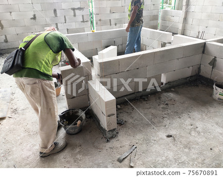 SEREMBAN, MALAYSIA -MARCH 15, 2020: Blockwork by construction workers at the construction site. Workers laying the AAC brick and stacked it together using mortar to form the wall. SEREMBAN, MALAYSIA -MARCH 15, 2020: Blockwork by construction workers at the construction site. Workers laying the AAC brick and stacked it together using mortar to form the wall. 75670891