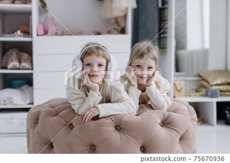 Girls sisters lie in a modern dressing room and look at the camera Girls sisters lie in a modern dressing room and look at the camera 75670936