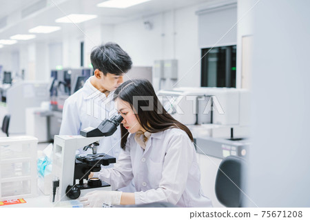 Two medical scientist working in Medical laboratory , young female scientist looking at microscope. select focus in young female scientist Two medical scientist working in Medical laboratory , young female scientist looking at microscope. select focus in young female scientist 75671208