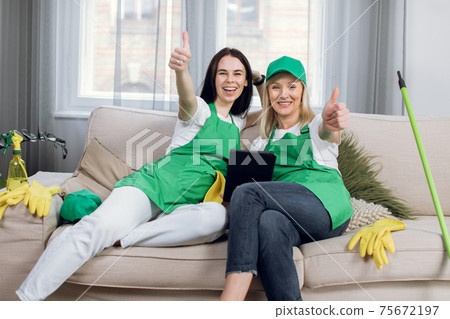 Smiling cleaners showing thumbs up and using tablet 75672197