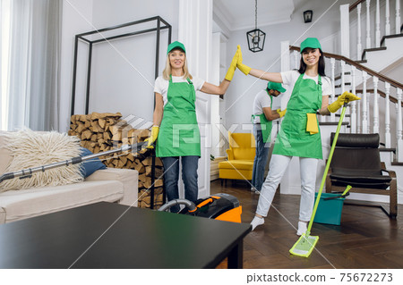 Women in uniform and gloves giving high five after cleaning Women in uniform and gloves giving high five after cleaning 75672273