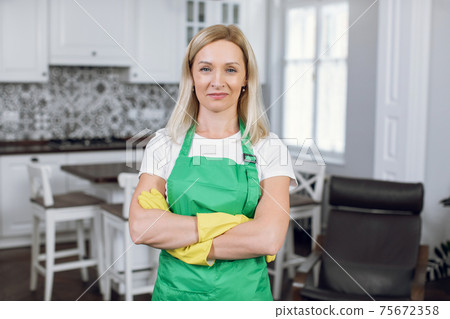 Portrait of woman in green apron and yellow gloves Portrait of woman in green apron and yellow gloves 75672358