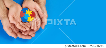 World Autism Awareness day, mental health care concept with puzzle or jigsaw pattern on heart with child and adult hands 75673698