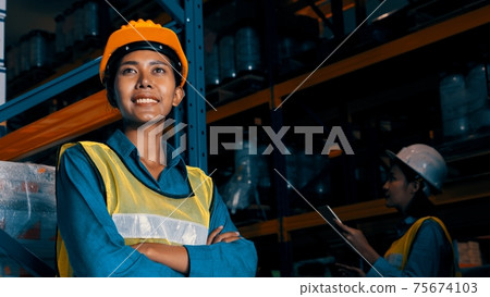 Portrait of young woman warehouse worker smiling in the storehouse Portrait of young woman warehouse worker smiling in the storehouse 75674103