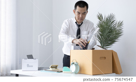 Put the work equipment in the office in a large brown box, Businessmen are keeping work documents and personal belongings due to resignation or being fired, termination of employment. Put the work equipment in the office in a large brown box, Businessmen are keeping work documents and personal belongings due to resignation or being fired, termination of employment. 75674547