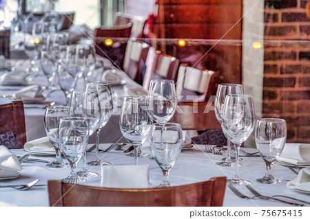 Restaurant interior with wine glasses and tableware and utensils on tables 75675415