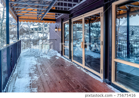 Front deck of building with double glass door and snow on the wooden floor 75675416