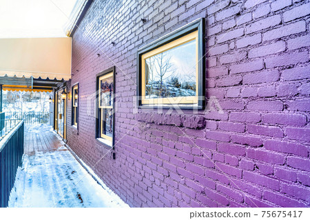 Building exterior with awning over the snowy wooden deck at the entrance 75675417