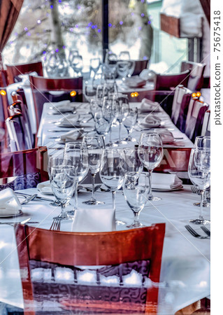 Interior of restaurant with tableware and utensils on tables with white cloth 75675418