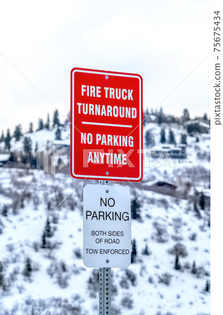 No Parking road signs against blurry background of snowy mountain and cloudy sky 75675434