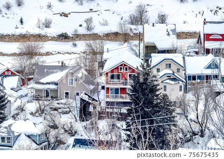 Beautiful family homes at scenic neighborhood in the snowy mountains in winter 75675435