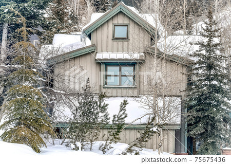 Exterior of home in the mountains with gray wall and snow covered roof in winter Exterior of home in the mountains with gray wall and snow covered roof in winter 75675436