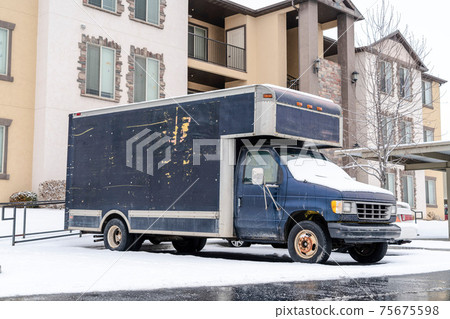 Small gray freight truck parked against the facade of a residential building Small gray freight truck parked against the facade of a residential building 75675598