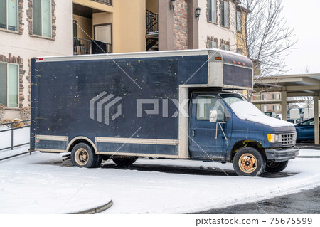 Commercial delivery truck parked in front of a residential building in winter 75675599