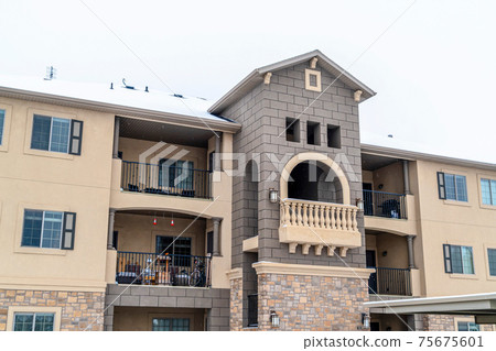 Three storey residential building with balcony and snowy roof against white sky Three storey residential building with balcony and snowy roof against white sky 75675601