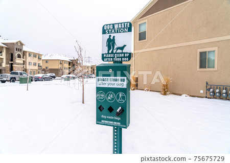 Dog waste station with pet poop bags dispenser in s snowy neighborhood in winter 75675729