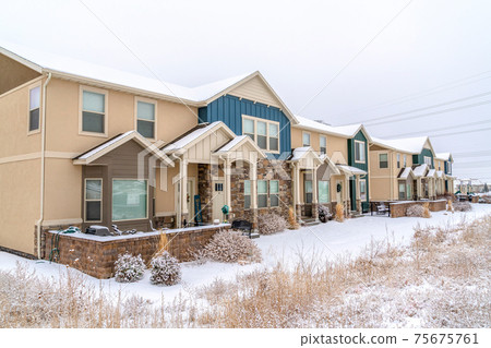 Apartment facade on a winter neighborhood with snow and cloudy sky views 75675761