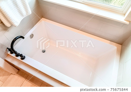 Built in rectangular bathtub with black gooseneck faucet inside home bathroom 75675844