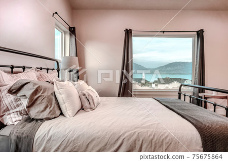 Relaxing double bed inside bedroom with scenic view of lake and mountain 75675864