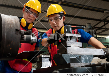 Group of skillful factory workers using machine equipment in workshop 75676862
