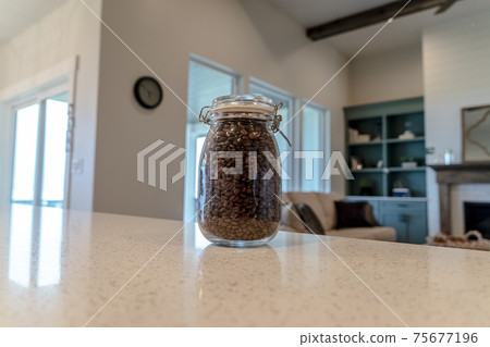 Jar of coffee beans on the glossy white counter top inside a home kitchen Jar of coffee beans on the glossy white counter top inside a home kitchen 75677196