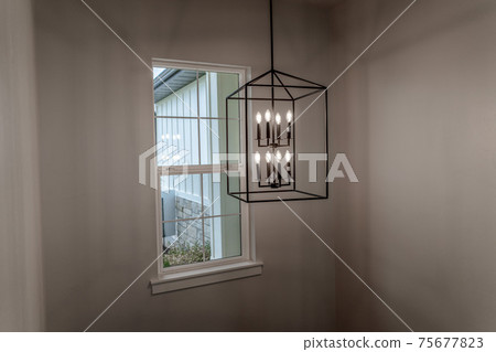 Geometric chandelier hanging from the ceiling of home against window and wall Geometric chandelier hanging from the ceiling of home against window and wall 75677823