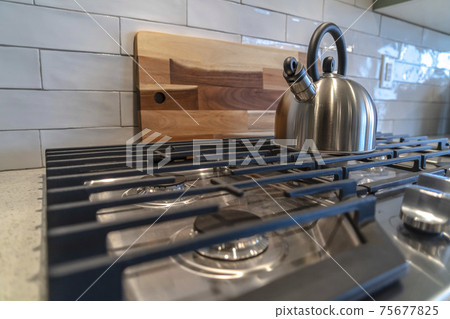 Cookpot with kettle against wooden chopping board and tile backsplash Cookpot with kettle against wooden chopping board and tile backsplash 75677825